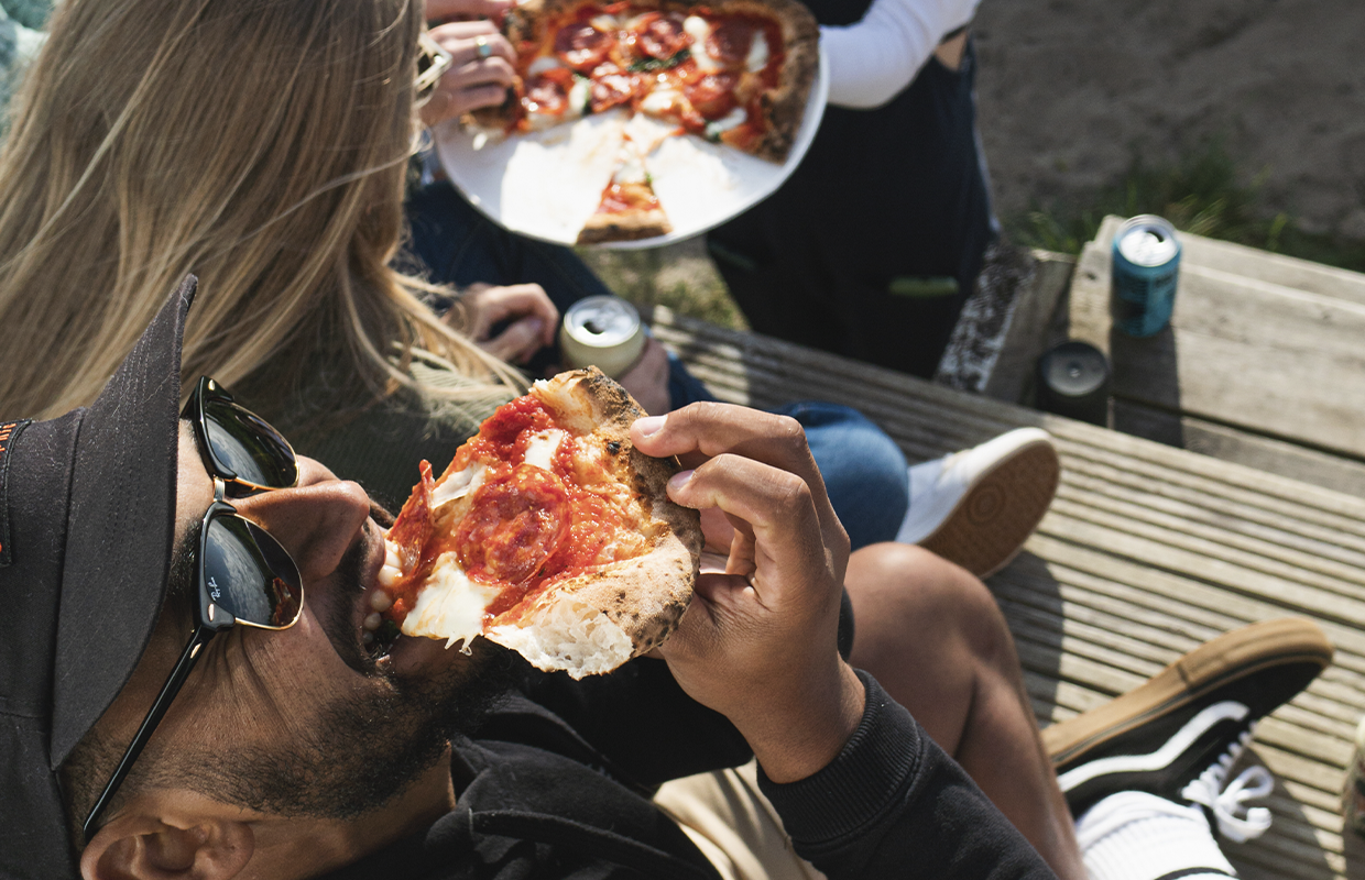 man eating pizza outdoors 
